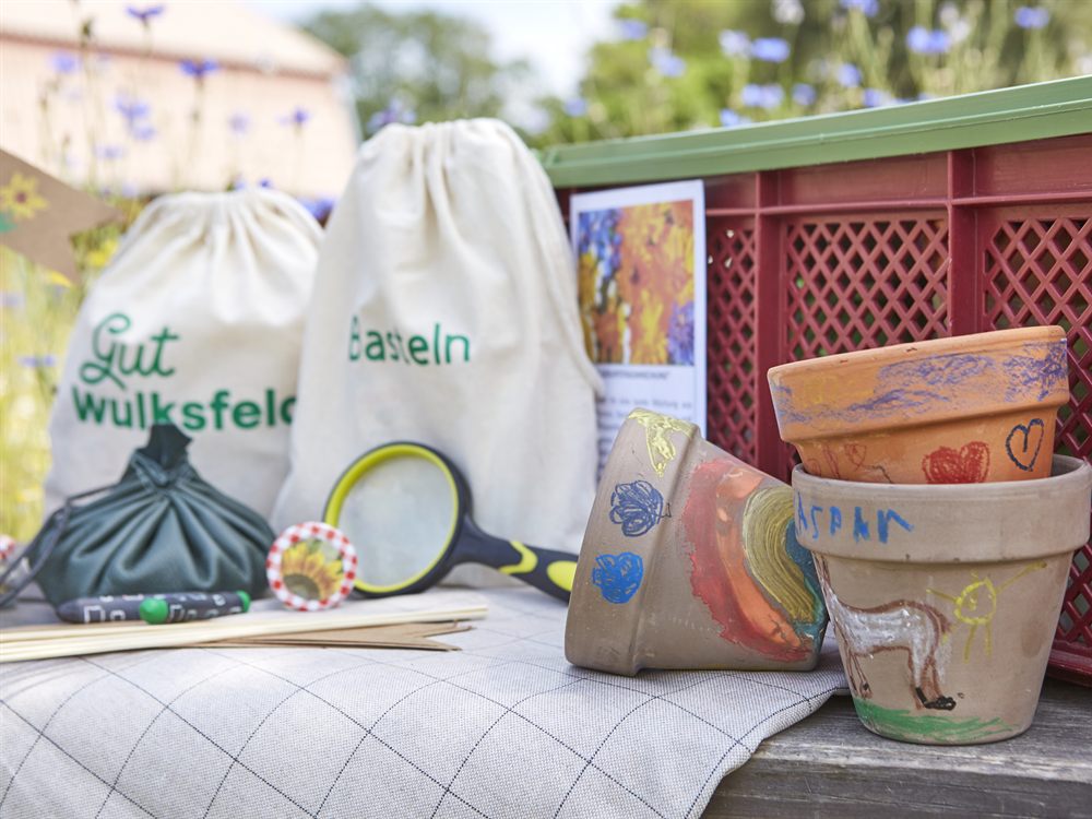 Selbst gestaltete Tontoepfe mit Wachsmalstiften bemalt, daneben Kreativmaterial